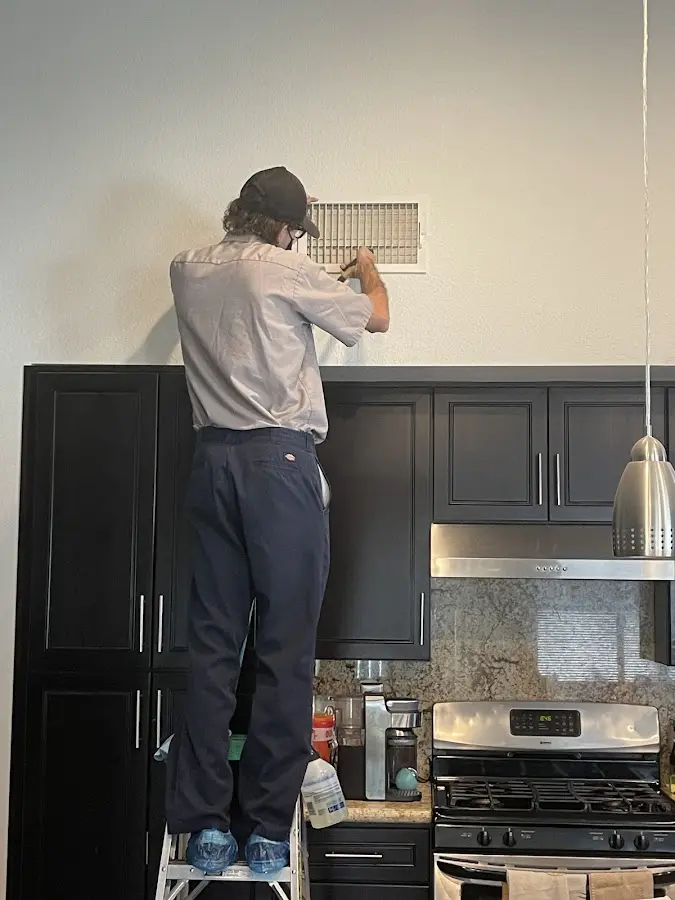 Technician inspecting an air vent during HVAC service in White Lake